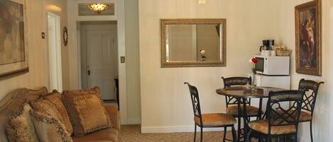 A dining area with a round table and chairs, a chandelier, and a mirror on the wall.