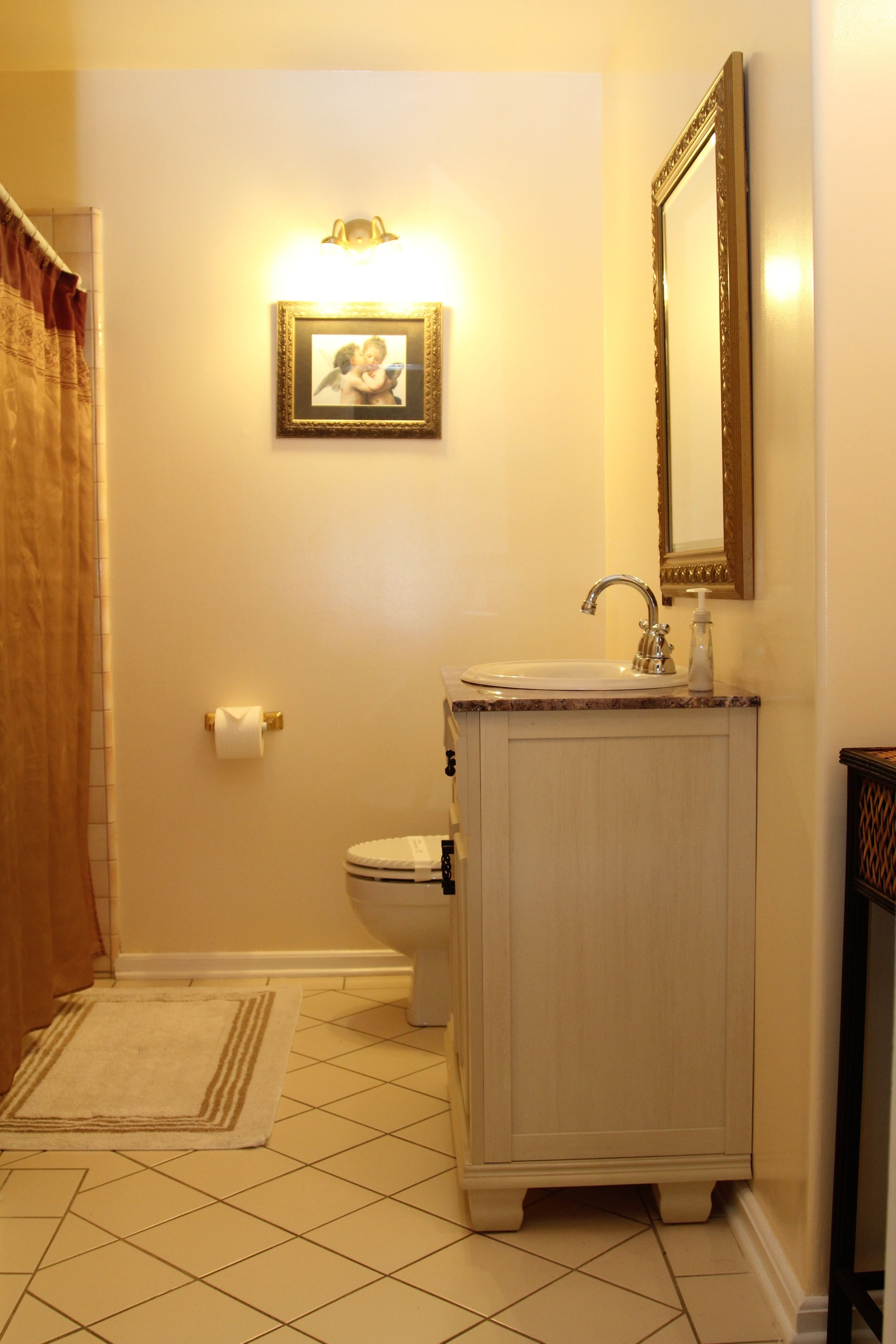 A bathroom with a toilet, sink, and mirror.