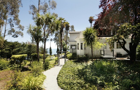 A pathway leading to a building surrounded by lush greenery and trees.
