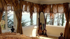 A room with a large bed, a mirror, and a view of the sea. - Monarch Cove Inn (Capitola)
