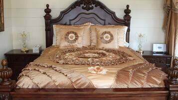 A bed with a ruffled bedspread and decorative pillows, wooden headboard, and matching nightstands with lamps.