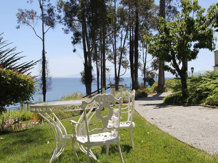 A white outdoor seating area with a view of the sea.