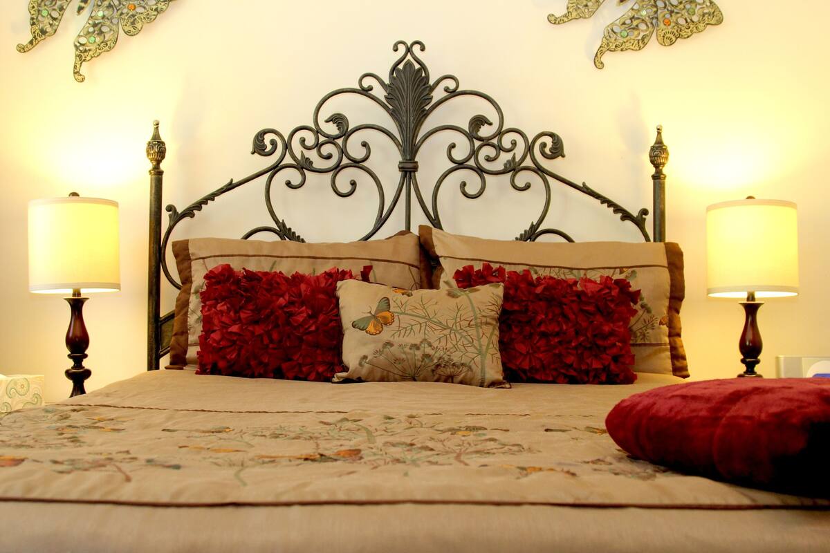 A bed with a decorative headboard, two bedside lamps, and floral-patterned bedding.