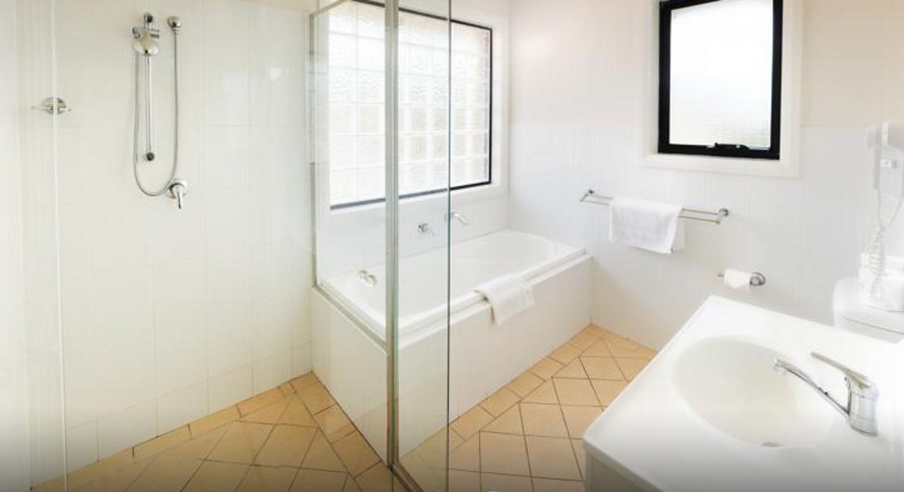 A bathroom with a glass-enclosed shower, a bathtub, and a sink.