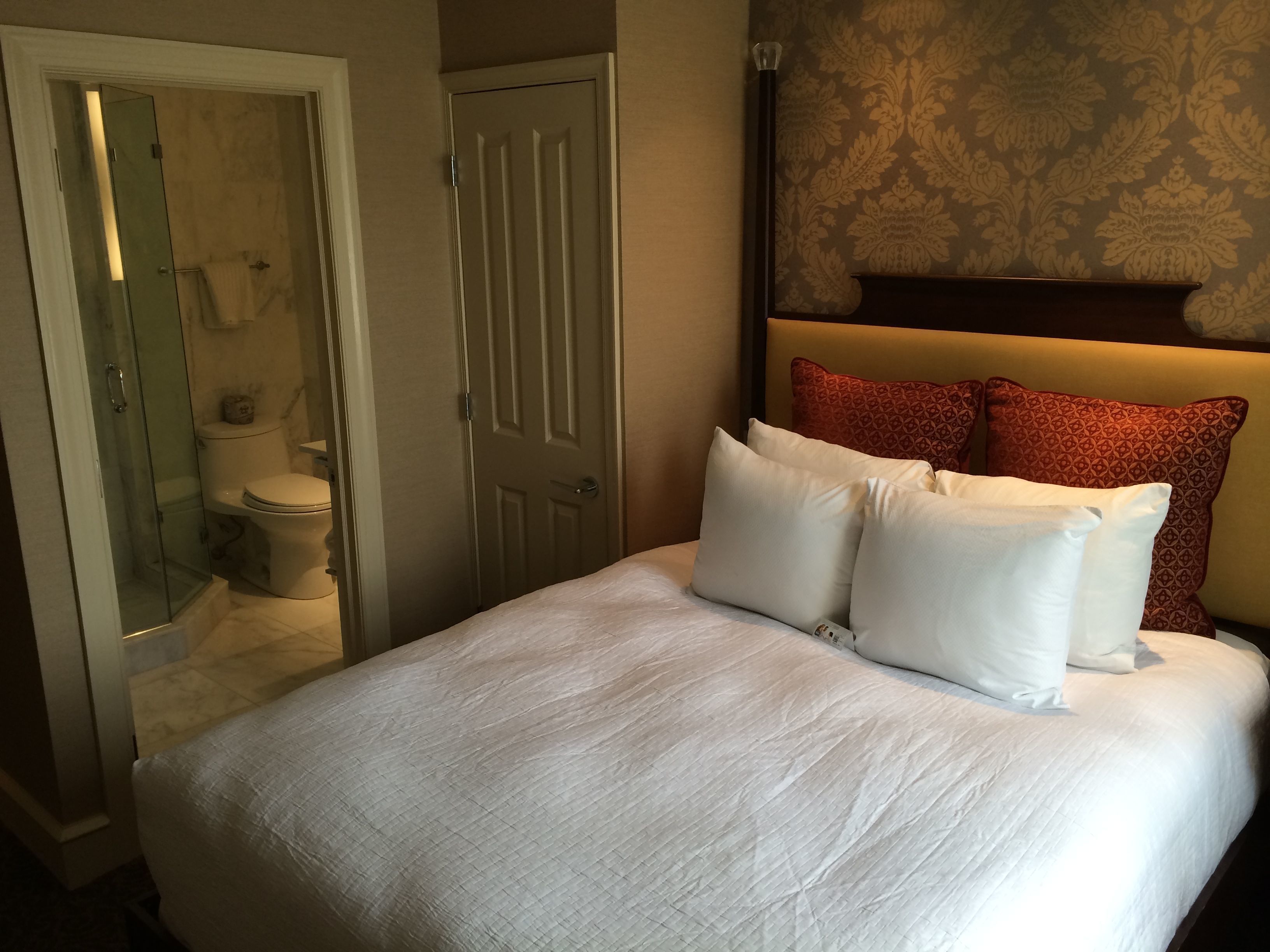 A hotel room with a bed, a bathroom, and a patterned wall.