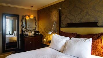 A hotel room with a large bed, a dresser, a mirror, and a nightstand with a lamp.