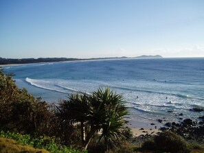 A coastal landscape with a beach, ocean waves, and a distant mountain range.