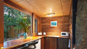 Une cuisine avec des meubles en bois, un four à micro-ondes, un évier et une fenêtre donnant sur un espace verdoyant.