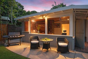 An outdoor patio with a grill, wicker chairs, and a table.