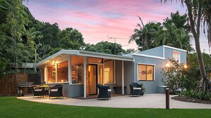 Une maison moderne dotée d’un patio couvert, d’un espace salon extérieur et d’une pelouse bien entretenue.