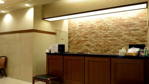 A reception area with a brick wall, wooden counter, and a bench. - Natural Hot Spring Midosuji Hotel (Osaka)