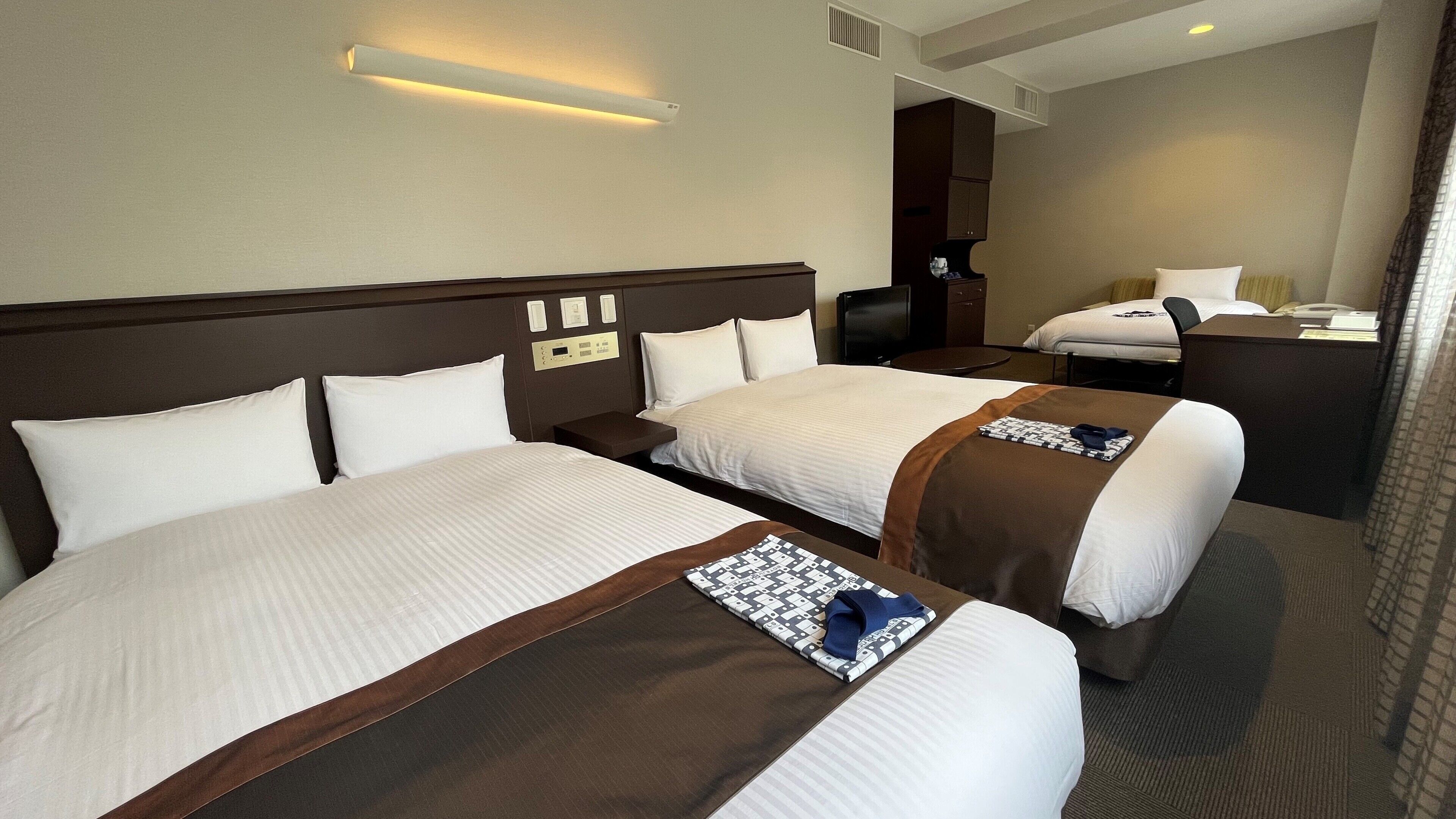 A hotel room with two beds, a desk, a chair, a TV, and a mirror.
