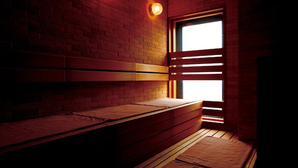 A room with a brick wall, wooden benches, and a window with blinds. - Natural Hot Spring Midosuji Hotel (Osaka)