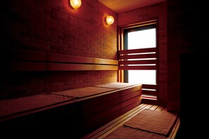 Een kamer met een bakstenen muur, houten banken en een raam met luiken.