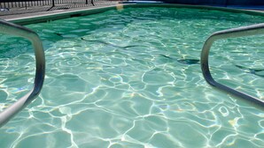 A clear swimming pool with visible water patterns and metal poolside railings. - Carlin Cottages (Calistoga)
