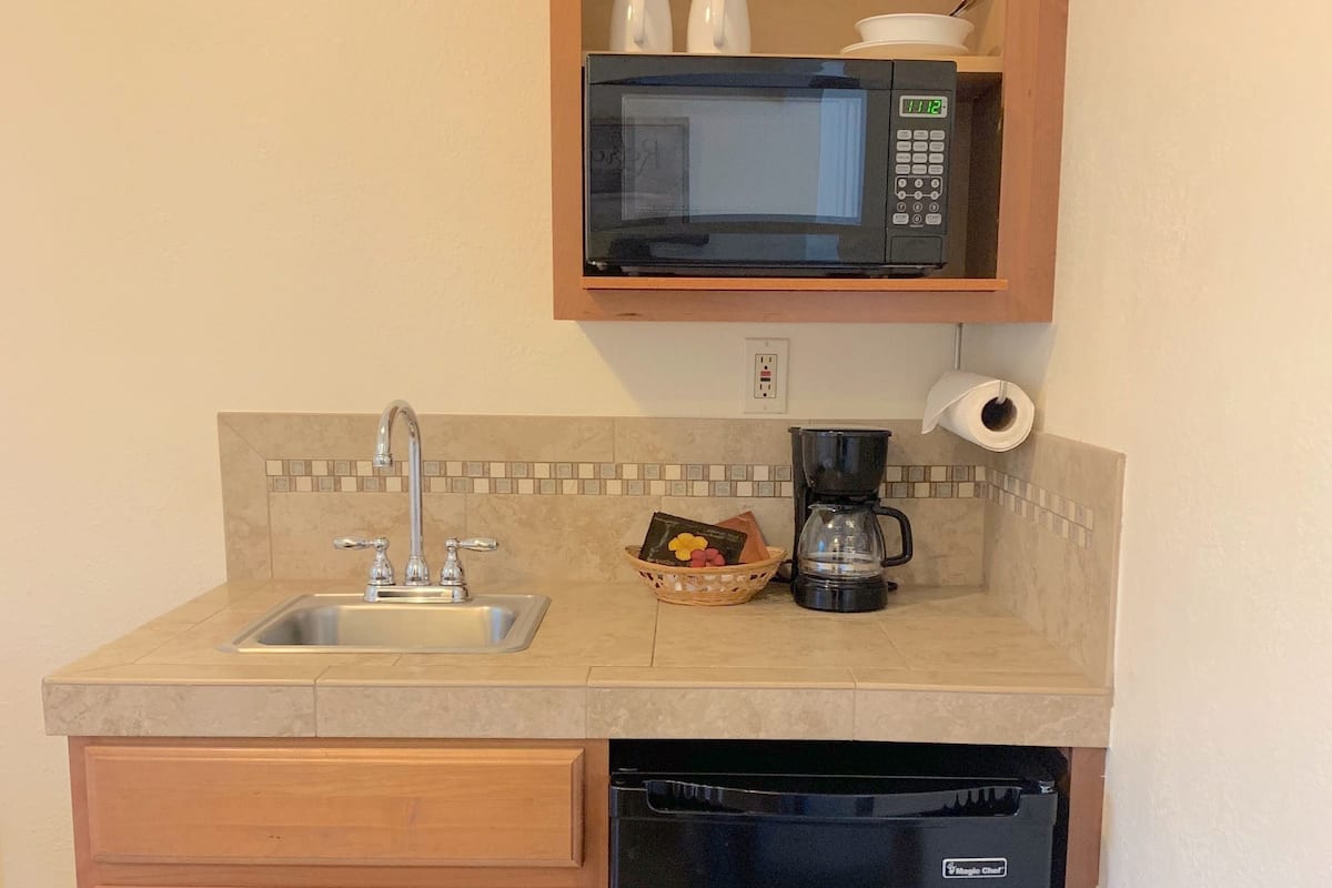 A compact kitchen with a sink, a microwave, a coffee maker, and a dishwasher.
