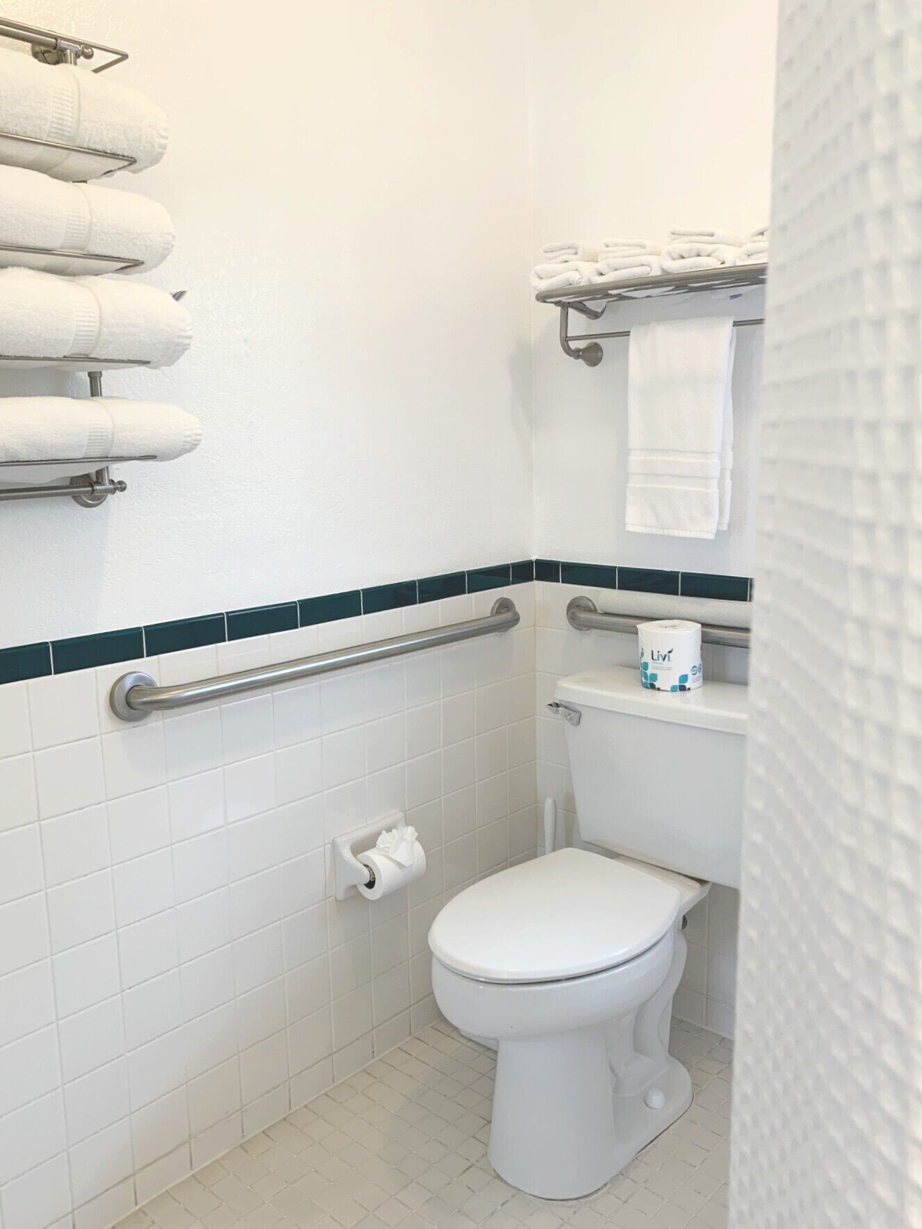 Een kleine, schone badkamer met toilet, een handgreep en een handdoekhouder.