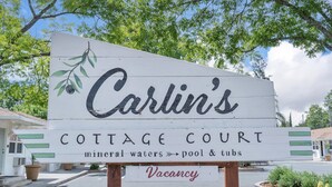 A sign for "Carlin's Cottage Court" with amenities like mineral waters, pool, and tubs, and a vacancy notice. - Carlin Cottages (Calistoga)