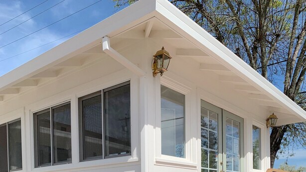 A white two-story house with a front porch, a staircase, and a small garden with a plant. - Carlin Cottages (Calistoga)