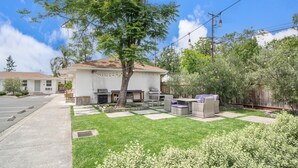 A residential property with a well-maintained lawn, outdoor seating area, and a barbecue setup. - Carlin Cottages (Calistoga)