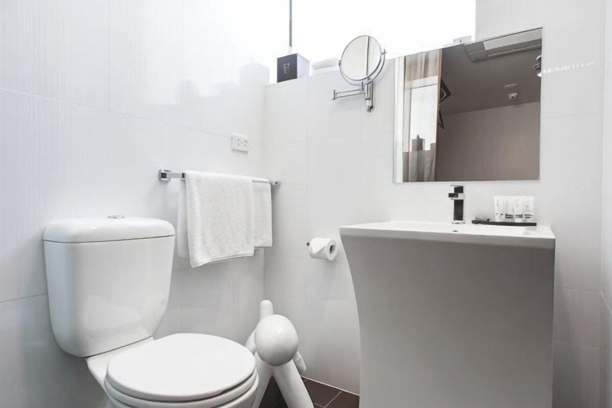 A modern bathroom with a toilet, sink, and mirror.