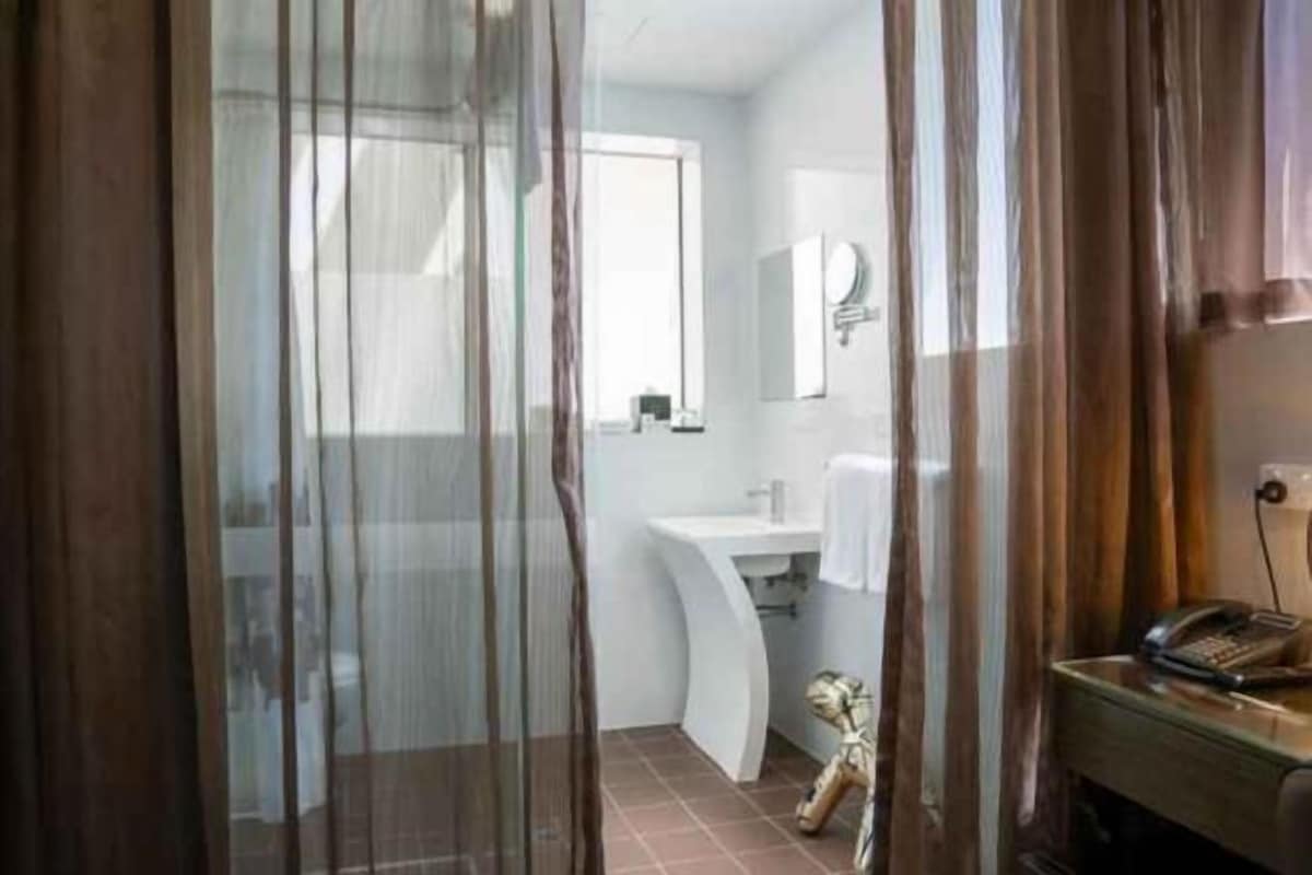 Une salle de bain avec un lavabo, un miroir et un téléphone posés sur une surface en bois.