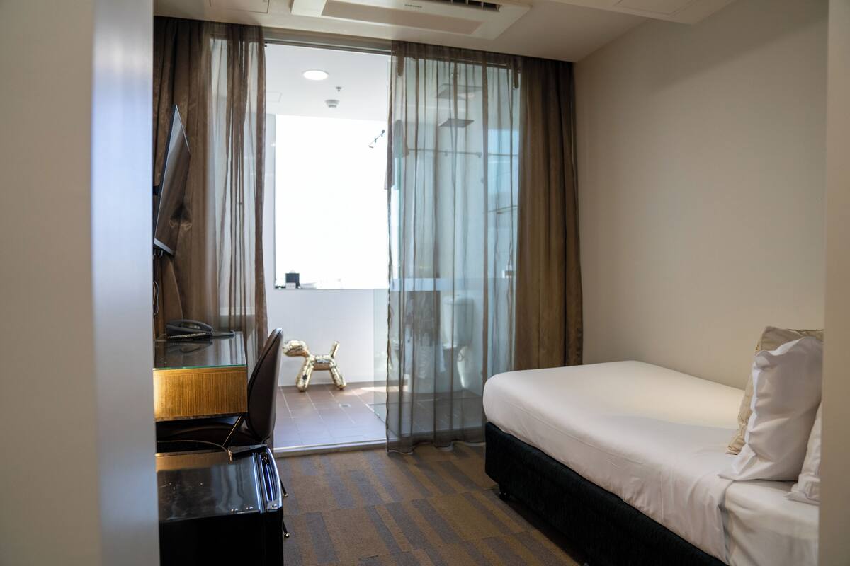 Una habitación de hotel con cama, escritorio, silla y una mesita.