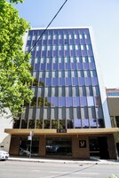 A modern hotel with a glass facade, numbered 57, and a 'One Way' sign visible at the entrance.