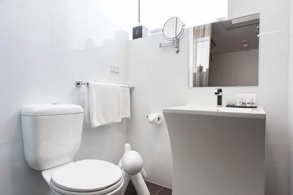 Un baño moderno con inodoro, lavamanos y espejo.