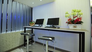 Un moderno mostrador de recepción con dos monitores de ordenador, un teléfono y un arreglo floral.