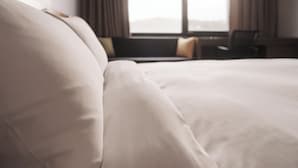A bed with a neutral-colored duvet in a hotel room. - Jeonju YeongHwa Hotel (Jeonju)