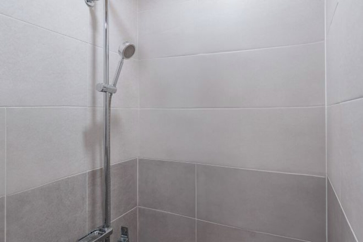 Esquina de un baño con azulejos blancos y zona de ducha.