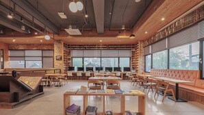 A library with wooden tables and benches, bookshelves, and large windows. - Jeonju YeongHwa Hotel (Jeonju)