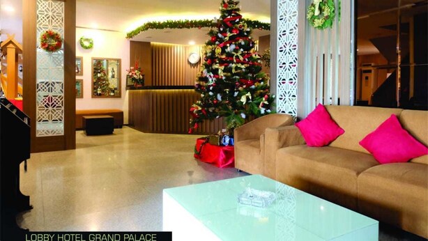 Um lobby com uma árvore de Natal, um sofá com almofadas cor-de-rosa e uma mesa de centro de vidro.