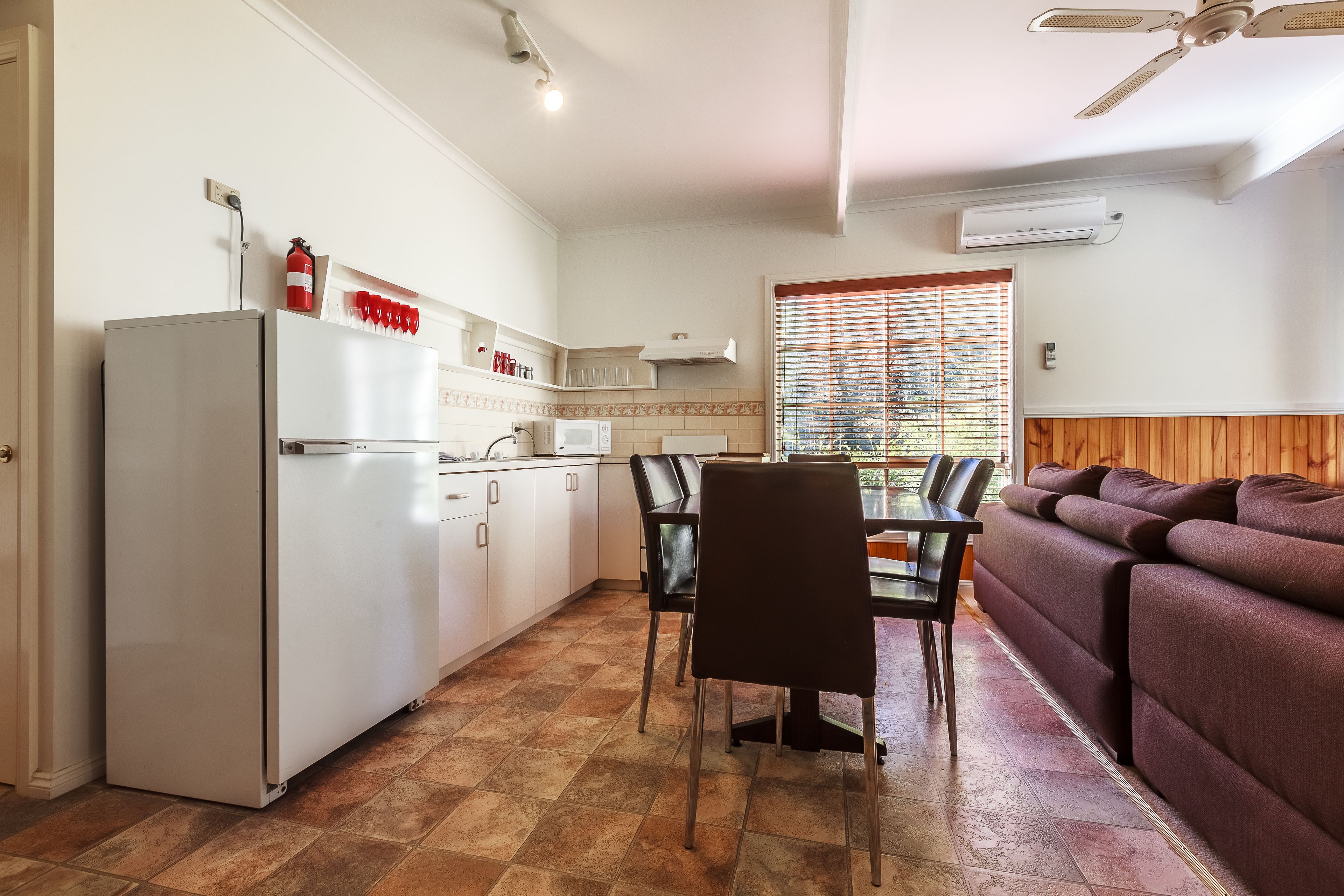 A compact kitchen with a refrigerator, microwave, and a dining area with chairs and a table.