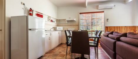 Una cocina compacta con refrigerador, microondas y un comedor con sillas y mesa.