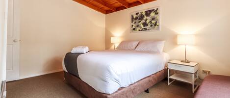 A bedroom with a bed, bedside tables, and a ceiling with wooden beams.