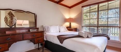 A bedroom with a bed, bedside table, lamp, and a large mirror.