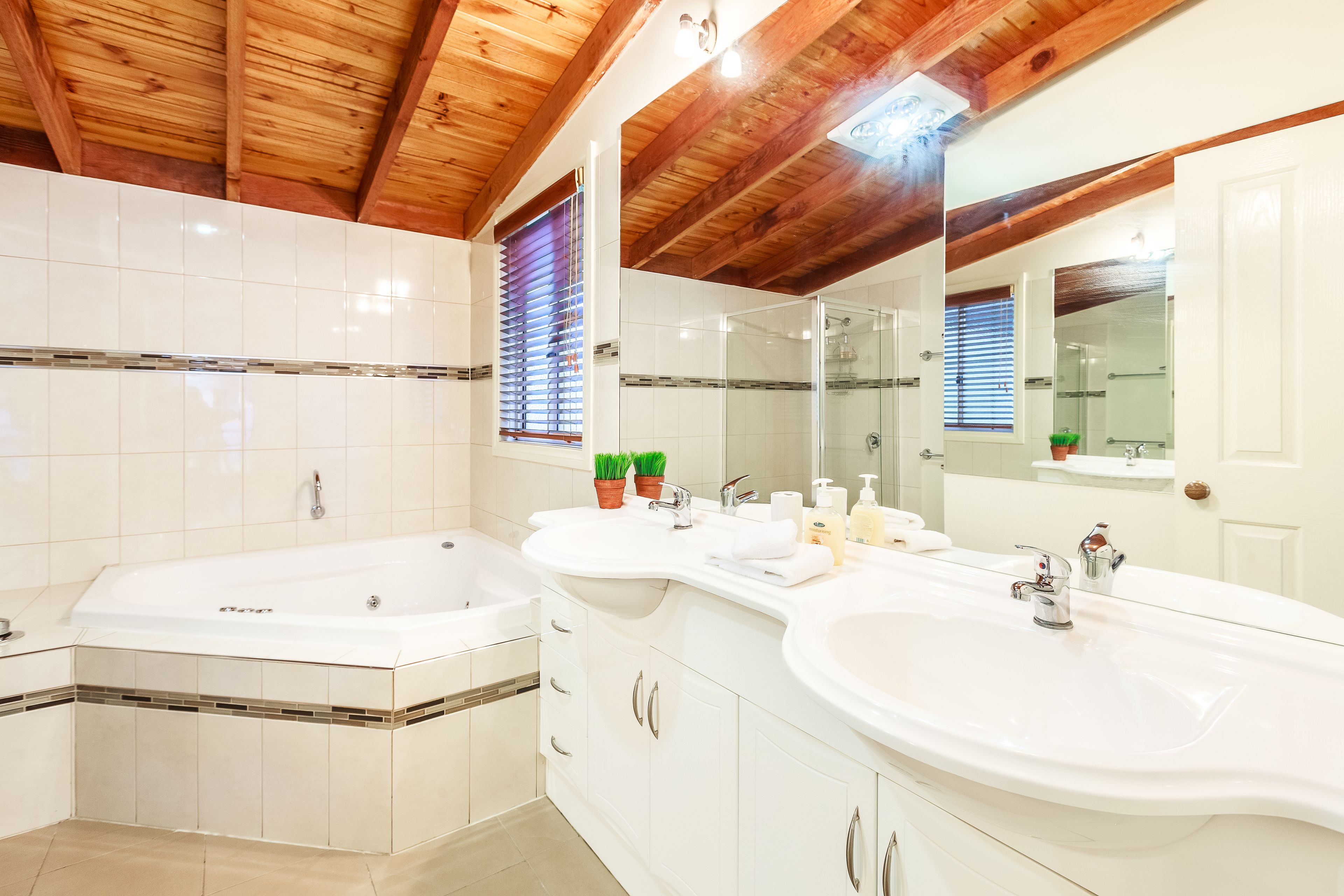 Une salle de bain moderne dotée d’une grande baignoire, de deux lavabos et d’une douche à l’italienne.
