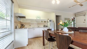 Una cocina moderna con armarios blancos, una mesa de comedor de madera y un ventilador de techo.