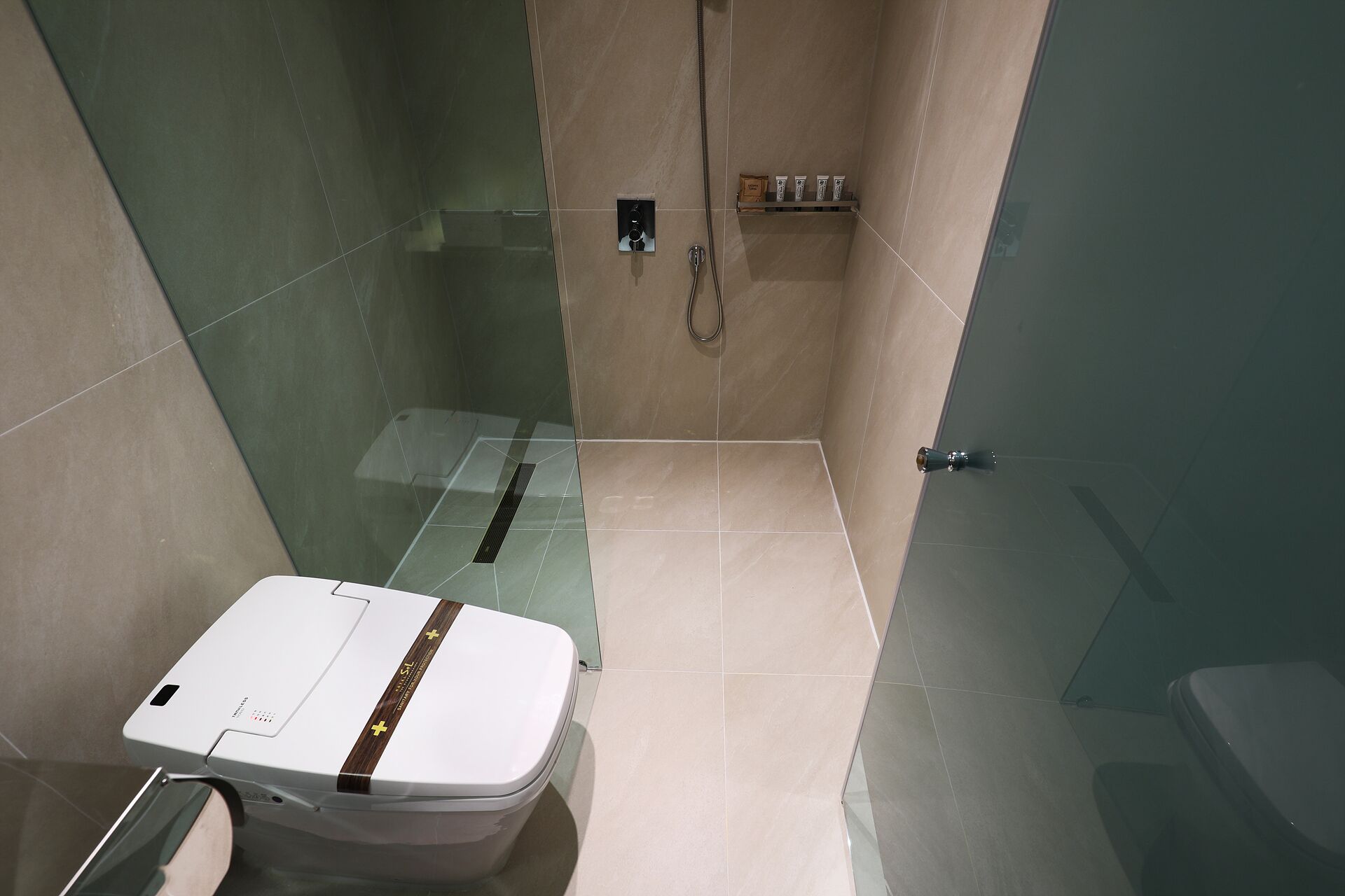 Un baño con inodoro, ducha y mampara de vidrio.