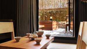 A traditional Japanese tea room with tatami flooring, a low wooden table, and a view of a garden through a sliding door. - Hotel SoL (Jeonju)