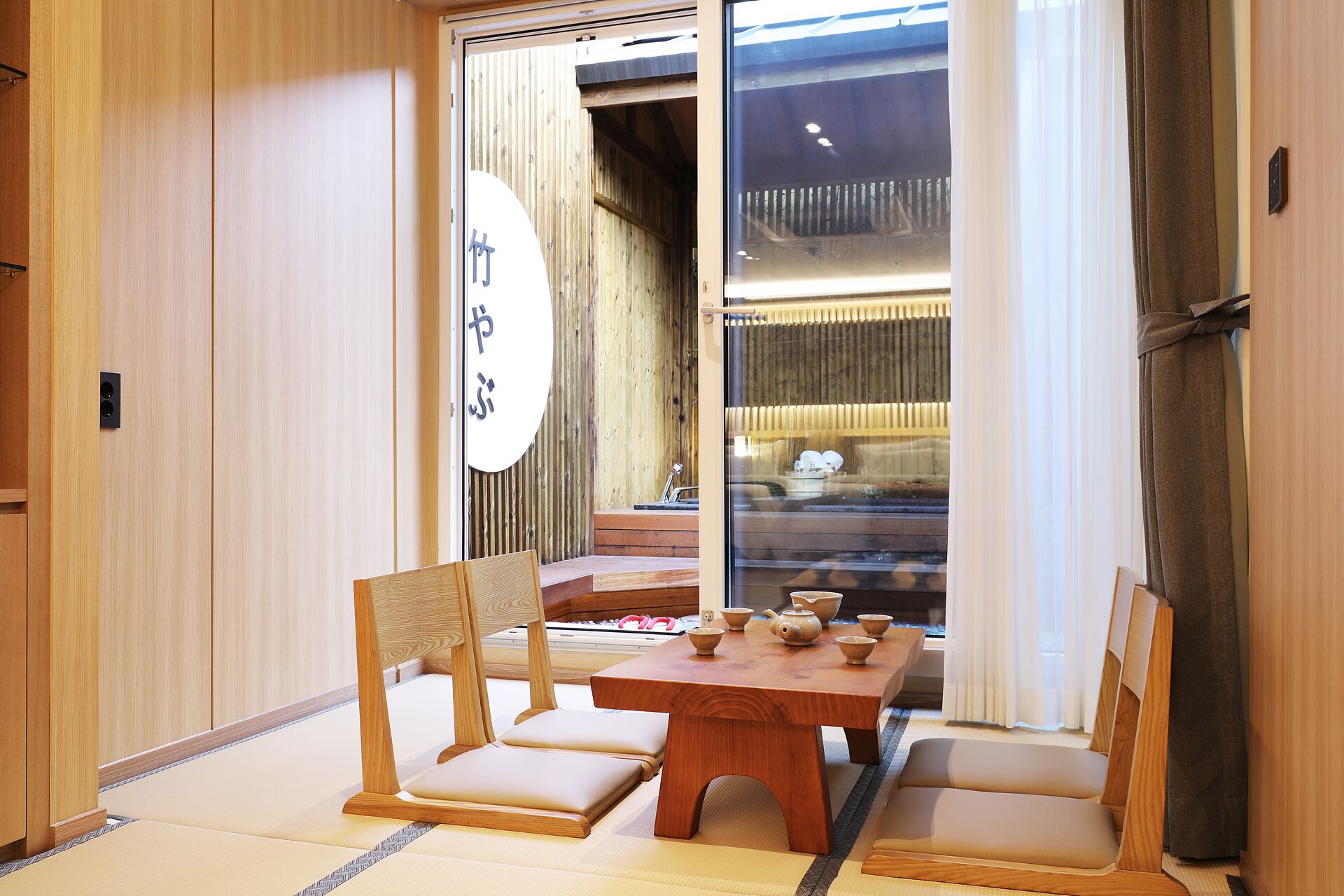 Une pièce de style japonais traditionnel, avec un sol recouvert de tatamis, une table en bois agrémentée d’un service à thé et des portes coulissantes dotées d’un intérieur en bois.