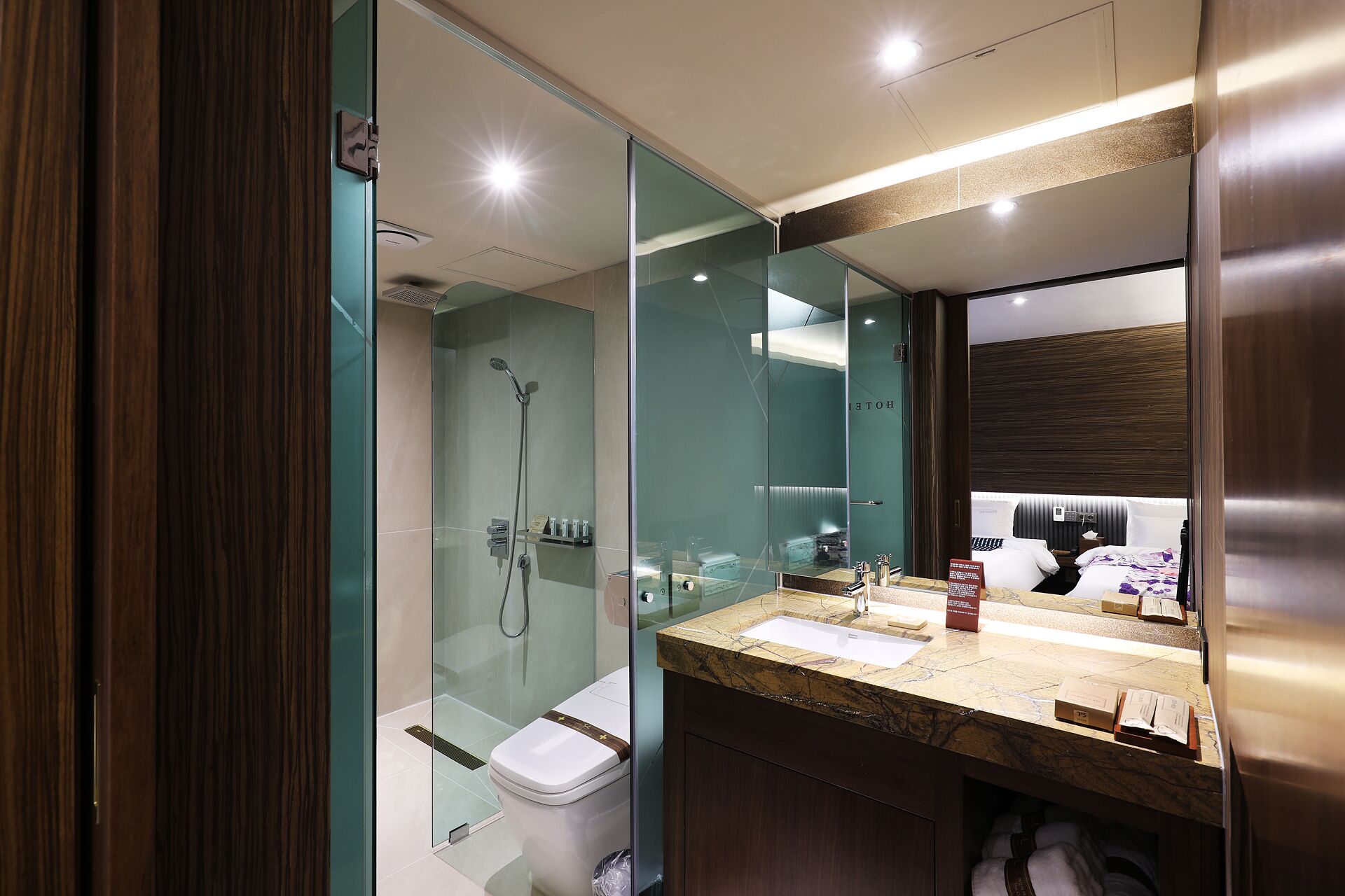A modern bathroom with a glass-enclosed shower, a marble sink, and a large mirror.
