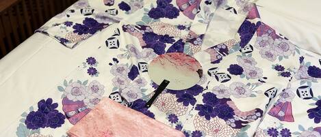 A bed with a floral patterned bedspread and a pink decorative item on it.