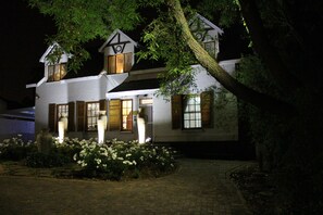 A two-story house with a sloped roof, large windows, and a well-maintained garden with white flowers. - 3Liebeloft Guest House (Edenvale)