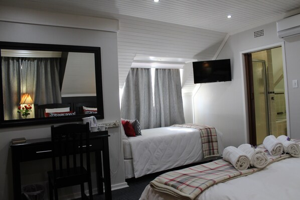 A hotel room with two beds, a desk, a chair, a TV, and a shower area. - 3Liebeloft Guest House (Edenvale)