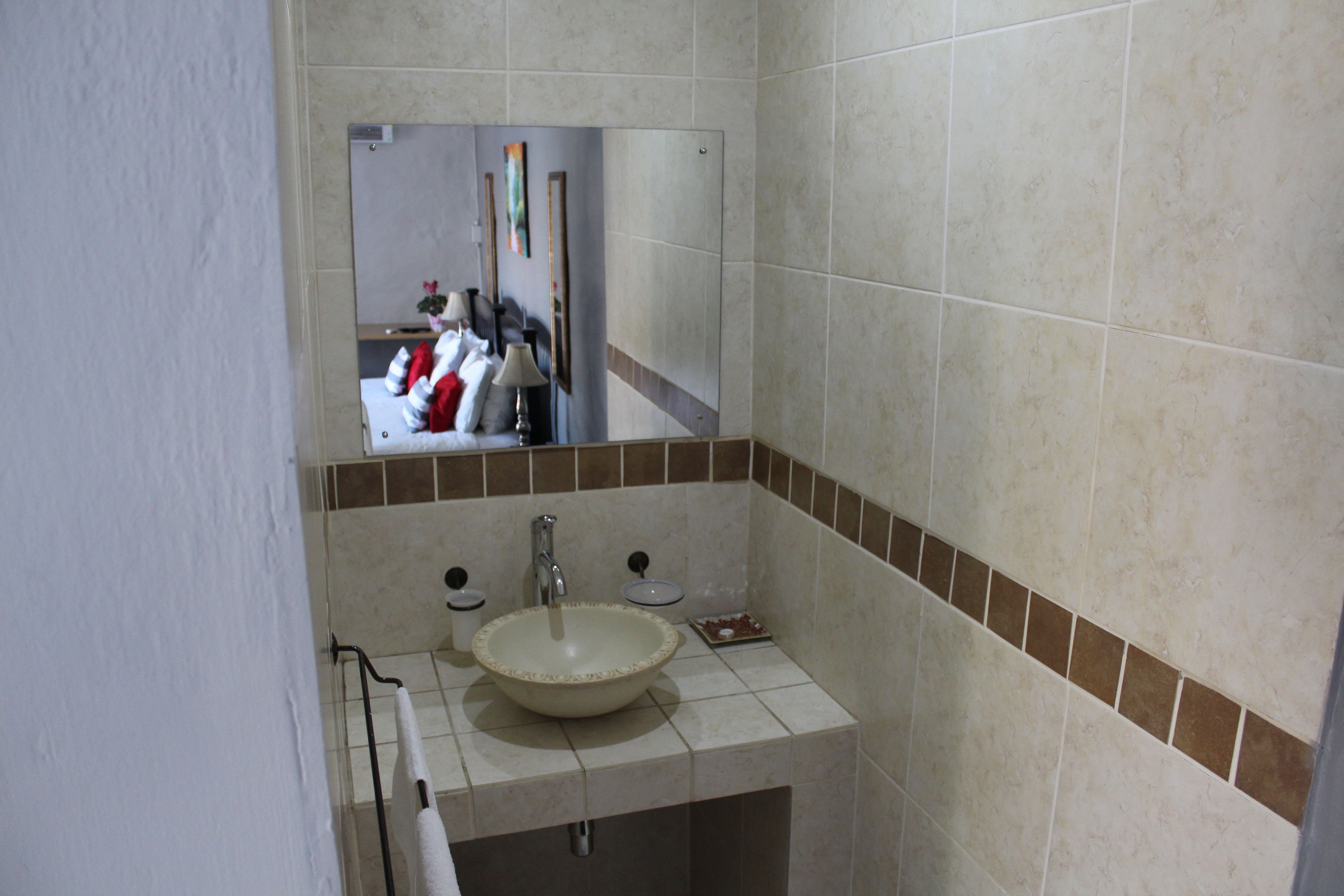 A bathroom with a sink, mirror, and tiled walls.