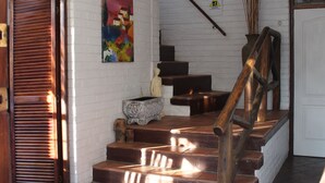 A staircase with wooden steps and a metal railing, leading to a landing with a red rug and a small table.