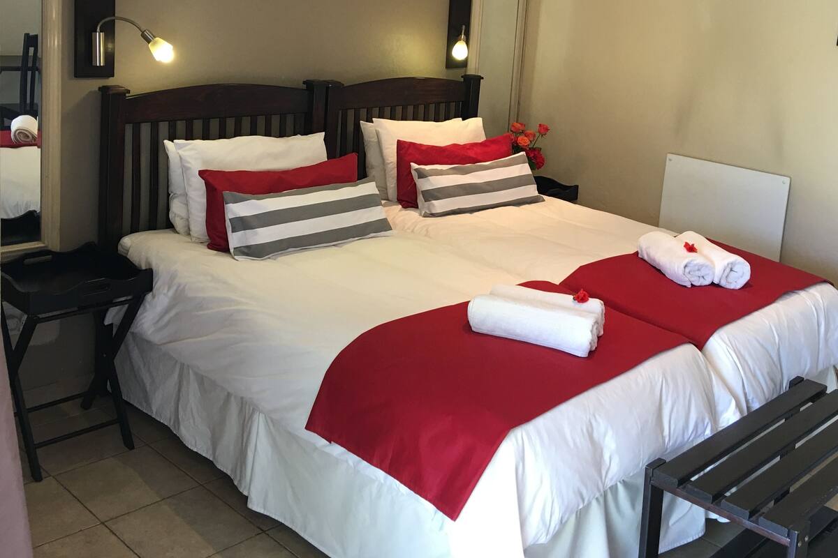 Ein Hotelzimmer mit einem großen Bett, zwei Nachttischen, einem Schminktisch und einer Bank.